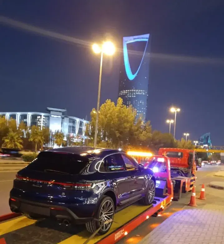 سطحة تابعة لسطحة إكسبريس تنقل بورش ماكان ليلاً قرب برج المملكة بالرياض