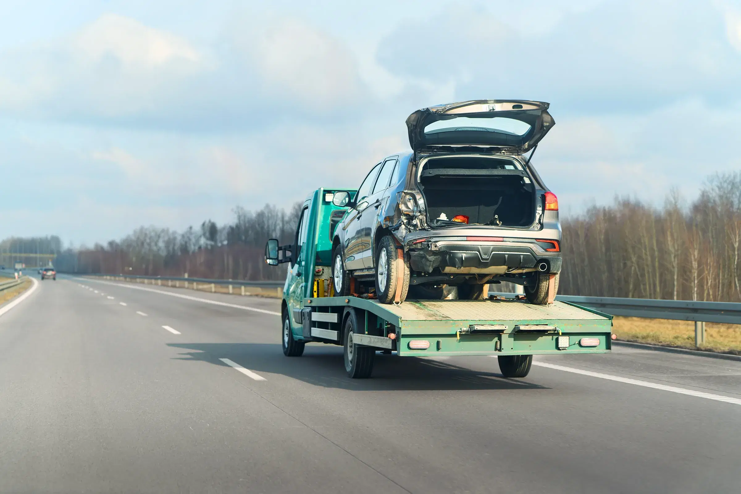 Flatbed truck transporting an accident-damaged vehicle